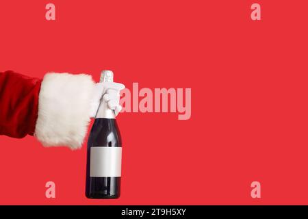 Der Weihnachtsmann hält eine Flasche Champagner auf rotem Hintergrund Stockfoto