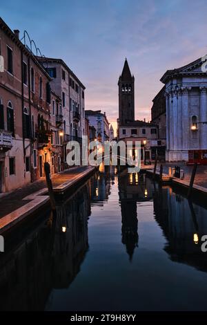 Venedig, Italien - 9. November 2023: Glockenturm der Chiesa di San Barnaba und schmaler Kanal in Venedig bei Sonnenaufgang Stockfoto