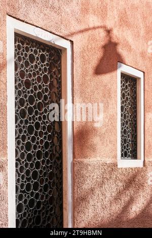 Venedig, Italien - 9. November 2023: Architektonische Details eines runden schmiedeeisernen Ornaments an Fenster- und Türöffnungen mit rosa Wänden Stockfoto