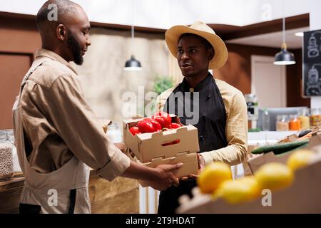 Ein afroamerikanischer Mann verkauft frische, biologische Produkte in einem umweltfreundlichen Supermarkt und bietet eine Vielzahl von nachhaltigem Obst und Gemüse für gesundheitsbewusste Kunden. Stockfoto