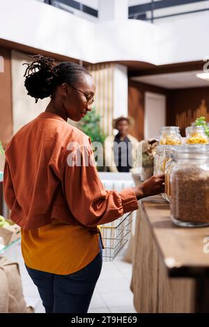 Afroamerikanische Kunden kaufen frische, lokal angebaute Produkte in einem Lebensmittelgeschäft. Sie überprüfen organische Optionen und erkunden umweltfreundliche Verpackungen. Das Geschäft bietet nachhaltige, verschwendungsfreie Auswahl für ein gesundes, bewusstes Einkaufserlebnis. Stockfoto