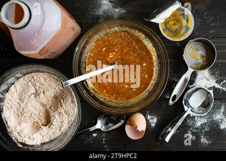 Mischen von feuchten Zutaten für gebackene Apfelwein-Donuts: Apfelsauce, griechischer Joghurt und andere Zutaten in einer Glasrührschüssel Stockfoto