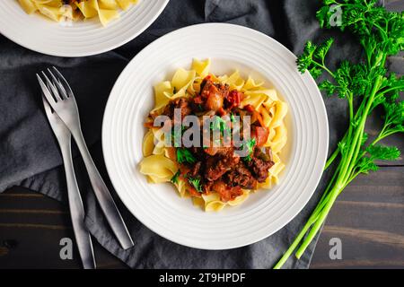 Deutscher Gulash serviert über Egg Nudeln in einer flachen Schüssel: Gekochte Rindfleischstücke mit Marjoram, Kümmel und Paprika Stockfoto