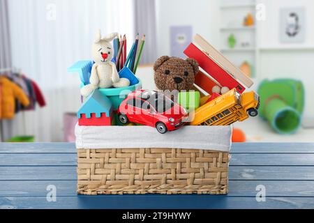 Korb mit vielen verschiedenen Spielzeugen auf blauem Tisch im Kindergarten Stockfoto