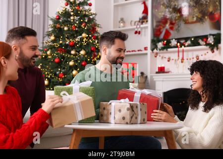 Glückliche Freunde tauschen zu Hause Weihnachtsgeschenke aus Stockfoto