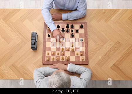 Männer spielen Schach während des Turniers am Holztisch, Blick von oben Stockfoto