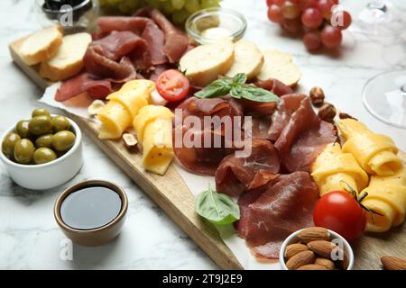 Charcuterie Board. Köstliche Bresaola und andere Snacks auf weißem Marmortisch Stockfoto