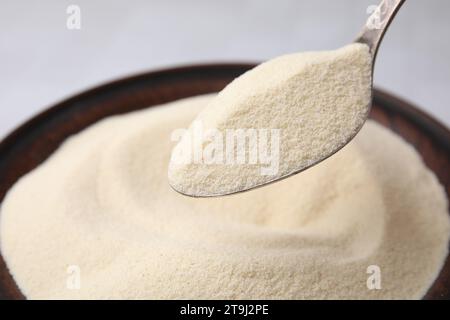 Ungekochter Bio-Grieß in Löffel über Schüssel, Großaufnahme Stockfoto