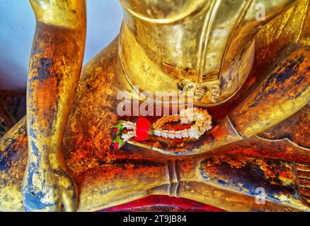 Nahaufnahme kleine Girlande auf der Hand eines alten goldenen Buddhas in einem Tempel, Landschaftsbild. Stockfoto