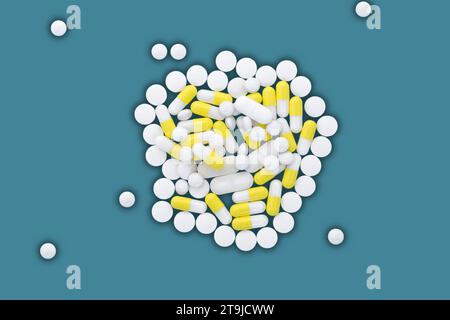 Ein Haufen weißer und gelber Pillen liegt auf blauem Hintergrund. Stockfoto