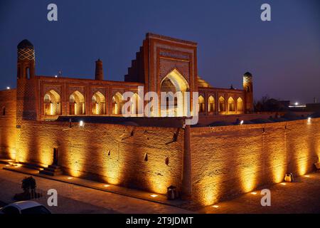 Historische Architektur Mohammed Rakhim Khan Madrassah mit Beleuchtung bei Sonnenuntergang in Itchan Kala Innenstadt der Stadt Chiwa, Usbekistan. Stockfoto