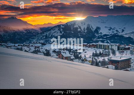 Fabelhaftes Wintergebirge mit schneebedeckten Gebäuden und frischem Schnee bei Sonnenaufgang, La Toussuire, Frankreich, Europa Stockfoto