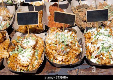 Schließen Sie die Behälter mit Fast Food auf braunem Tisch mit leeren Schildern. Knusprige Pommes mit Knoblauch-Parmesan, Ranch-Dressing und Stockfoto