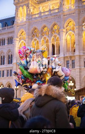 Verkäufer von Ballons für Kinder in der Menge des Weihnachtsmarktes (Wiener Christkindlmarkt) nachts im Winter, Rathause, Wien, Österreich Stockfoto