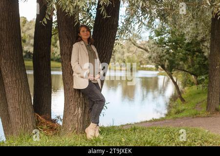 Schöne schwangere Frau, die im Sommerpark im Freien ruht Stockfoto