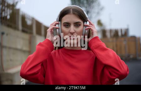 Porträt einer Running Woman nach Joggen im Park auf der Herbstsonde. Ein weibliches Fitnessmodell trainiert draußen an einem gemütlichen Herbsttag und hört Musik Stockfoto