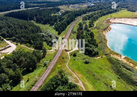 Eine Eisenbahnlinie, die neben einem überfluteten Steinbruch vorbeiführt, aus der Luft Stockfoto