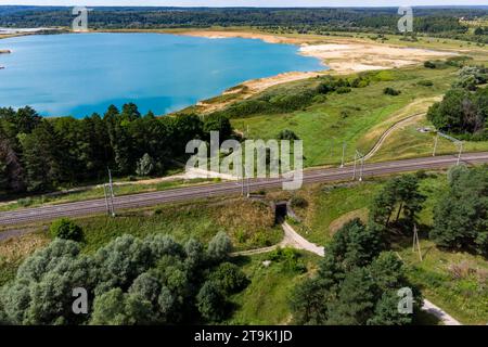 Aus der Vogelperspektive der in der Nähe des blauen Sees vorbeifahrenden Bahn, einem Tunnel unter dem Bahndamm Stockfoto