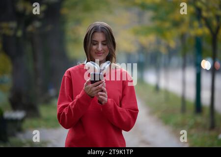 Sportliche Frau überprüft das Smartphone, bevor sie einige Übungen macht, hört Musik aus einer Playlist Stockfoto