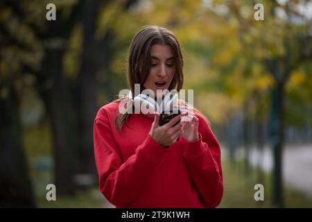 Sportliche Frau überprüft das Smartphone, bevor sie einige Übungen macht, hört Musik aus einer Playlist Stockfoto