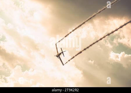 Das Flugzeug hinterlässt Rauch und fliegt bei Sonnenuntergang gegen den Himmel. Stockfoto
