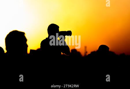 Eine Silhouette eines Fotografen mit einer Kamera bei Sonnenuntergang. Stockfoto