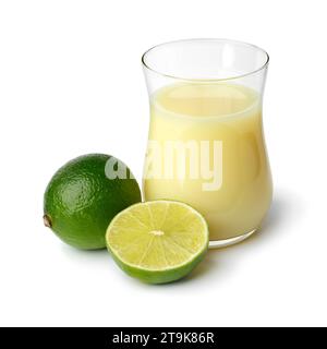 Glas mit Limettensaft und ganzer und halber grüner Limette vorne, isoliert auf weißem Hintergrund Stockfoto