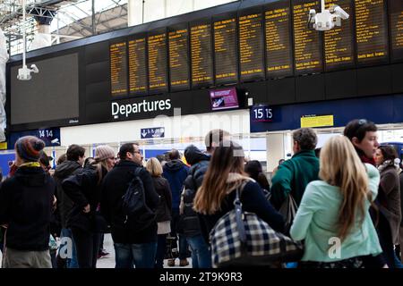 Gruppe von Personen, die die elektronischen Abfahrten am Bahnhof Paddington in London beobachten Stockfoto