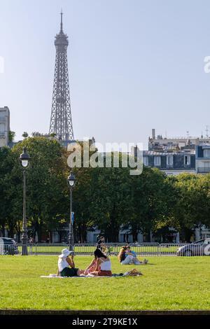 Paris, Frankreich - 8. Oktober 2023 : Freunde sitzen auf dem Gras und genießen einen schönen Tag und den Eiffelturm im Hintergrund in Paris Frankreich Stockfoto