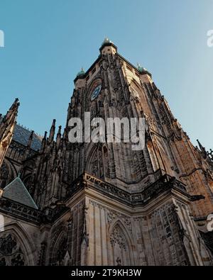 Eine gotische Kathedrale mit zwei Türmen und einem Zifferblatt vor blauem Himmel. Die mittelalterliche gotische St. Veitsdom in Prag. Stockfoto