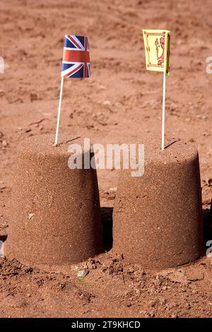 Zwei Sandburgen am Strand im Sommer mit einer britischen und walisischen Flagge oben Stockfoto