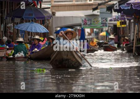 Damnoen Saduak, Thailand - 10. August 2007: Zwei thailändische Frauen im Kanu, eine paddelnd, während ihre älteste die Aussicht zu schätzen weiß. Sie gehen zum Schwimmen Stockfoto