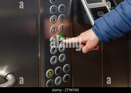 Ein Mann drückt im Fahrstuhl des Business Centers auf den Fußbodenknopf. Stockfoto