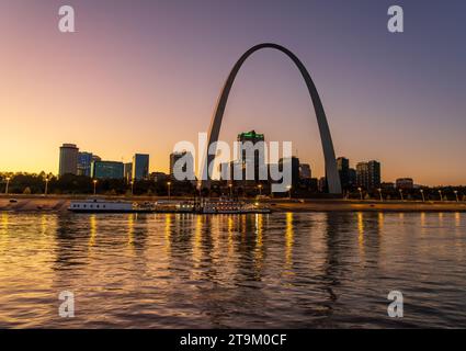 Niedrige Wasserstände im Mississippi River mit Reflexionen des Gateway Bogens, der bei glühendem Sonnenuntergang und Sonnenuntergang über dem Ufer thront Stockfoto
