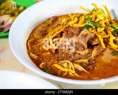 Khao Soi, Thai-Nudelcurry-Suppe mit gedünstetem Rindfleisch (khao Soi nuer) in weißer Schüssel, Nahaufnahme. Berühmte lokale Küche im Norden Thailands. Stockfoto