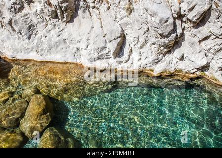 Wassergrün ist klar im Reservoir in der Schlucht zwischen Steinen, leichte Beeinträchtigung der Oberfläche. Stockfoto