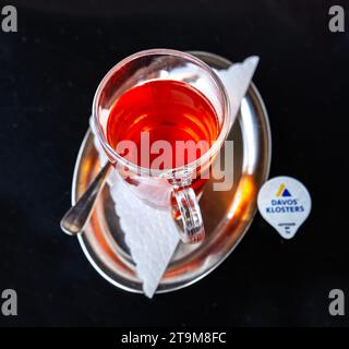 Glasbecher Tee auf einem kleinen, glänzenden ovalen Metalltablett mit einem kleinen Milchkarton Stockfoto
