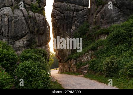 Das Morgenlicht leuchtet durch die Lücke zwischen den Externsteinen auf dem Wanderweg, der durch diese bizarre Sandsteinformation in Deutschland führt Stockfoto