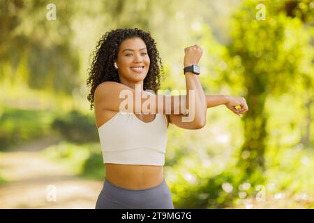 Die junge, sportliche Frau arbeitet an ihrer Flexibilität und dehnt die Arme im Freien aus Stockfoto