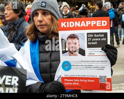 London, Großbritannien. November 2023. Nationaler Solidaritätsmarsch gegen Antisemitismus, organisiert von der Kampagne gegen Antisemitismus. Die Organisatoren riefen dazu auf, dass die Menschen dieses Landes sich der jüdischen Gemeinde anschließen und solidarisch marschieren. Die Marschierenden trafen sich und bildeten sich an den königlichen Justizgerichten und marschierten zum Parlamentsplatz. Frau, die teilweise in israelischer Flagge gehüllt ist und ein Plakat mit der Aufschrift „Entführt“ hält. Bitte bringen Sie sie lebend nach Hause, mit dem Bild des 27-jährigen Israelis Ofir Sarfati. Quelle: Stephen Bell/Alamy Live News Stockfoto