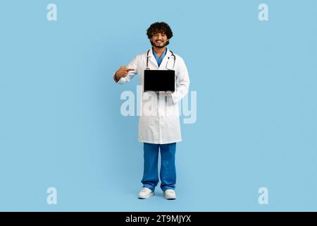 Lächelnder indianer Doktor zeigt Computer mit weißem Bildschirm Stockfoto