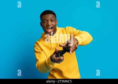 Emotionaler junger schwarzer Mann, der Videospiele mit Joystick spielt Stockfoto