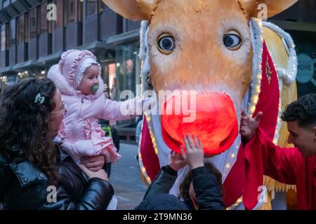 Glasgow, Schottland, Großbritannien. November 2023. Ein junger Bewunderer trifft Rudolf, den Rotnasen-Rentier, während des jährlichen Stilmeile Christmas Carnival in der Buchanan Street. Quelle: Skully/Alamy Live News Stockfoto