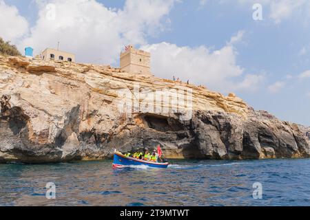 Blaue Grotte, Malta - 25. August 2019: Touristen segeln auf dem Meer vor Torri Xutu. Antiker Wachturm in der Nähe der Blauen Grotte von Malta Stockfoto