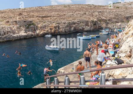 Blue Grotto, Malta - 22. August 2019: Blick auf die Küste mit dem Hafen der Blauen Grotte. Holzboote liegen vor dem öffentlichen Strand voller Menschen auf einem vor Anker Stockfoto