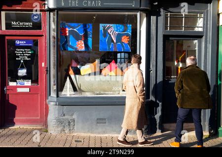 Menschen, die Gemälde im Fenster der Stuhlgalerie Hay-on-Wye bei Christimas während der Buchfestivals des Hay Winter Festivals in Wales ansehen, Großbritannien KATHY DEWITT Stockfoto