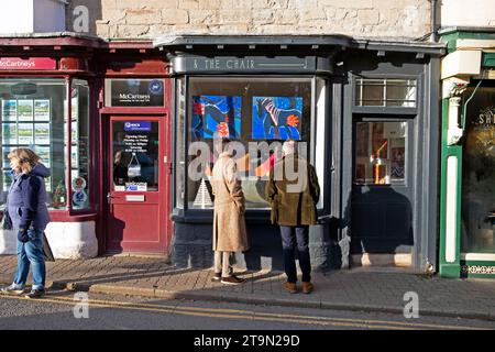Menschen, die Gemälde im Fenster der Stuhlgalerie Hay-on-Wye bei Christimas während der Buchfestivals des Hay Winter Festivals in Wales ansehen, Großbritannien KATHY DEWITT Stockfoto