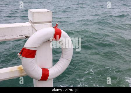 Weißer Rettungsschirm am Strand. Sicherheit auf dem Wasser, Rettungsring auf Sturmmeerhintergrund Stockfoto