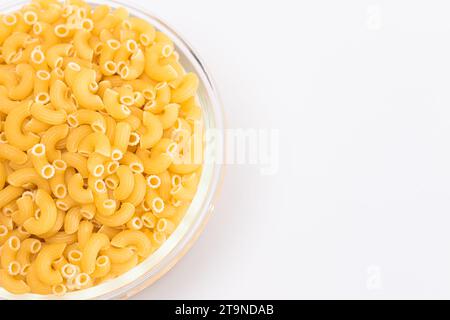 Ungekochte Chifferi Rigati Pasta im Glas auf weißem Hintergrund. Fett und ungesunde Lebensmittel. Klassische Trockene Makkaroni. Italienische Kultur und Küche. Rohe Pasta Stockfoto