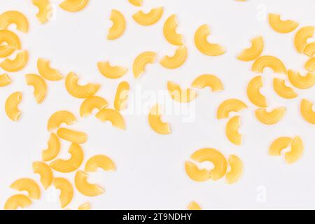 Verstreute ungekochte Chifferi Rigati Pasta auf weißem Hintergrund. Fett und ungesunde Lebensmittel. Klassische Trockene Makkaroni-Textur. Italienische Kultur und Küche. Rohe Pasta Stockfoto